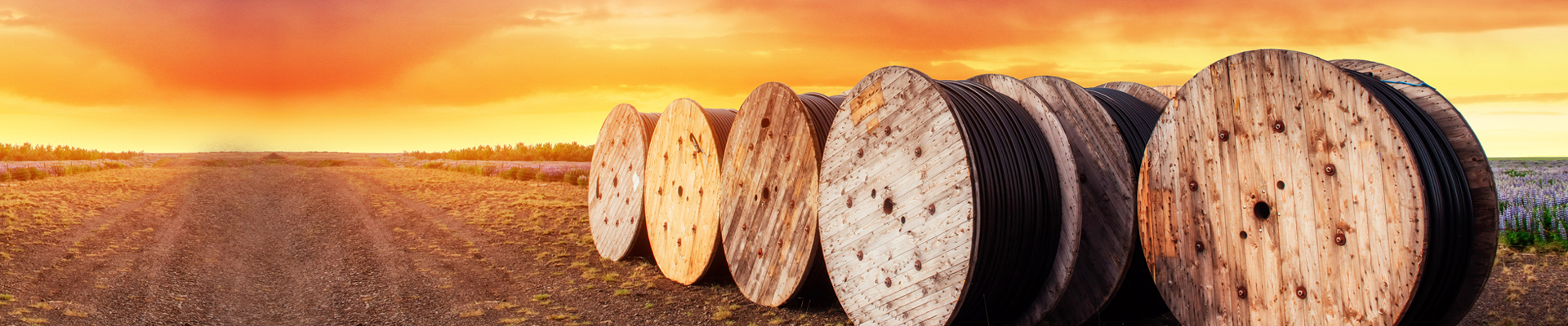 Cable reels on a field with the sunset in the background