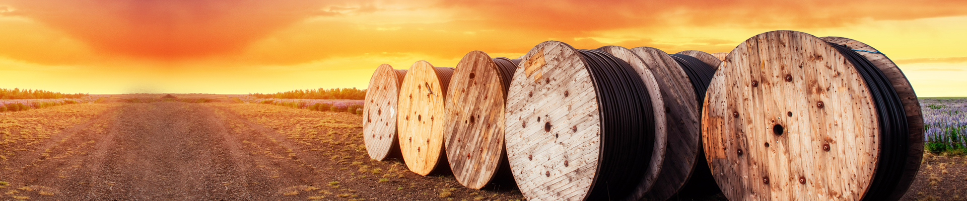 Make cables out of Emoltene plasticizer Cable reels on a field with the sunset in the background