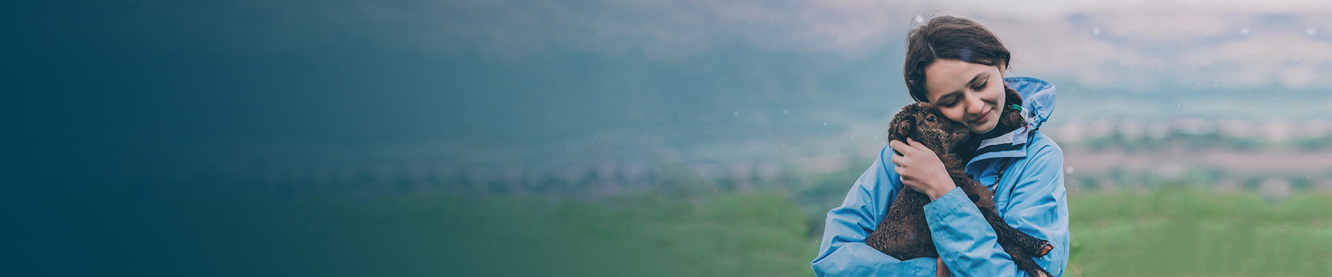 Girl in a blue jacket holding a brown lamb