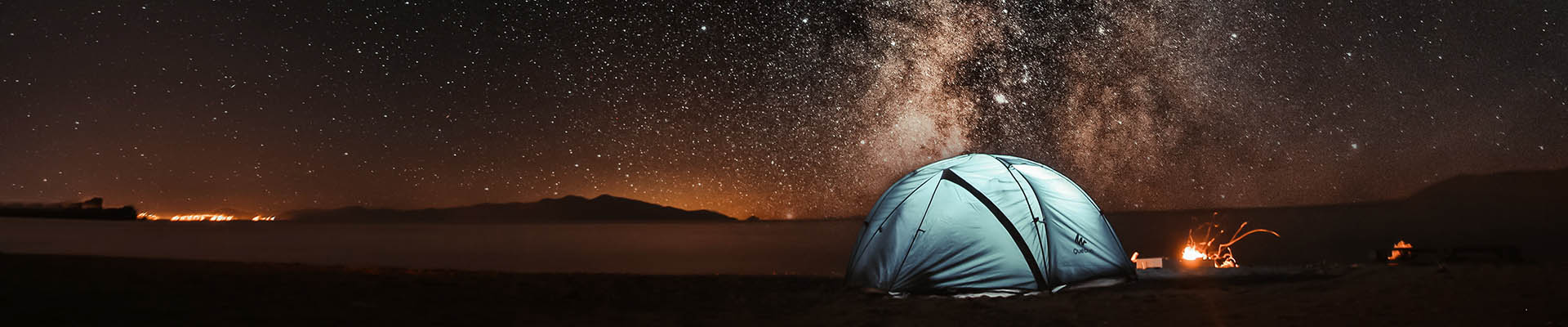 A blue tent out it the desert under a starry nigh