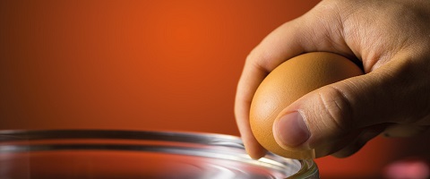 Egg cracking against bowl