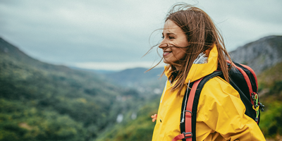 Pevalen Woman outdoors in the forest wearing a yellow raincoat