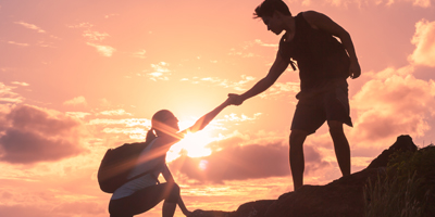 Challenges A man helping a woman climb up a rock
