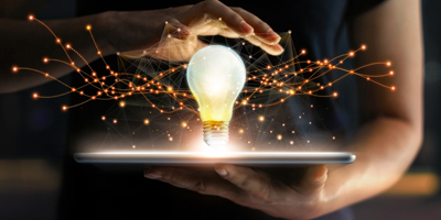 Solutions Person holding a tablet with a lightbulb on top of it