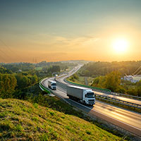 Trucks driving on a highway amongst green hills